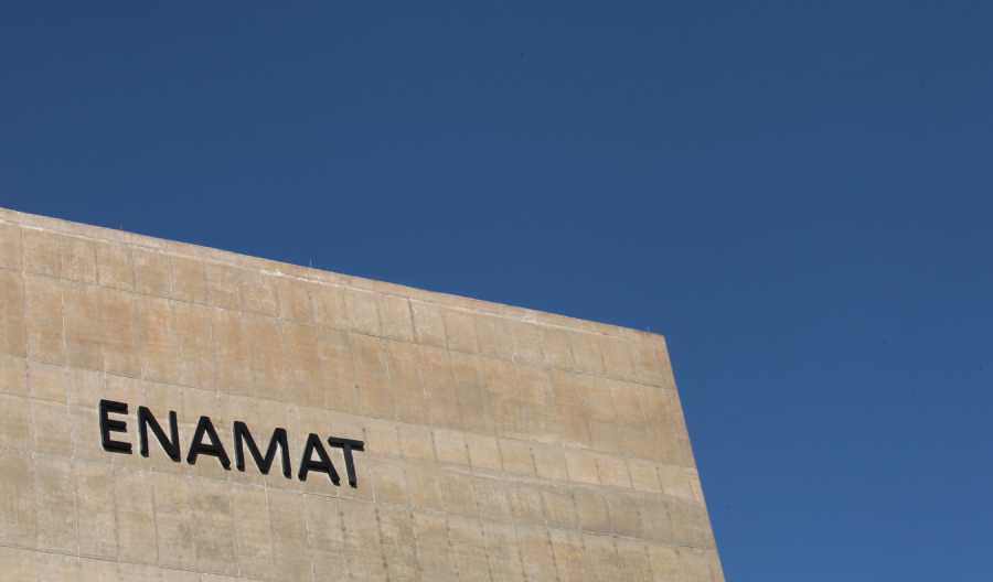 Foto da fachada da Enamat (parede de concreto e letras caixa presta escrito 